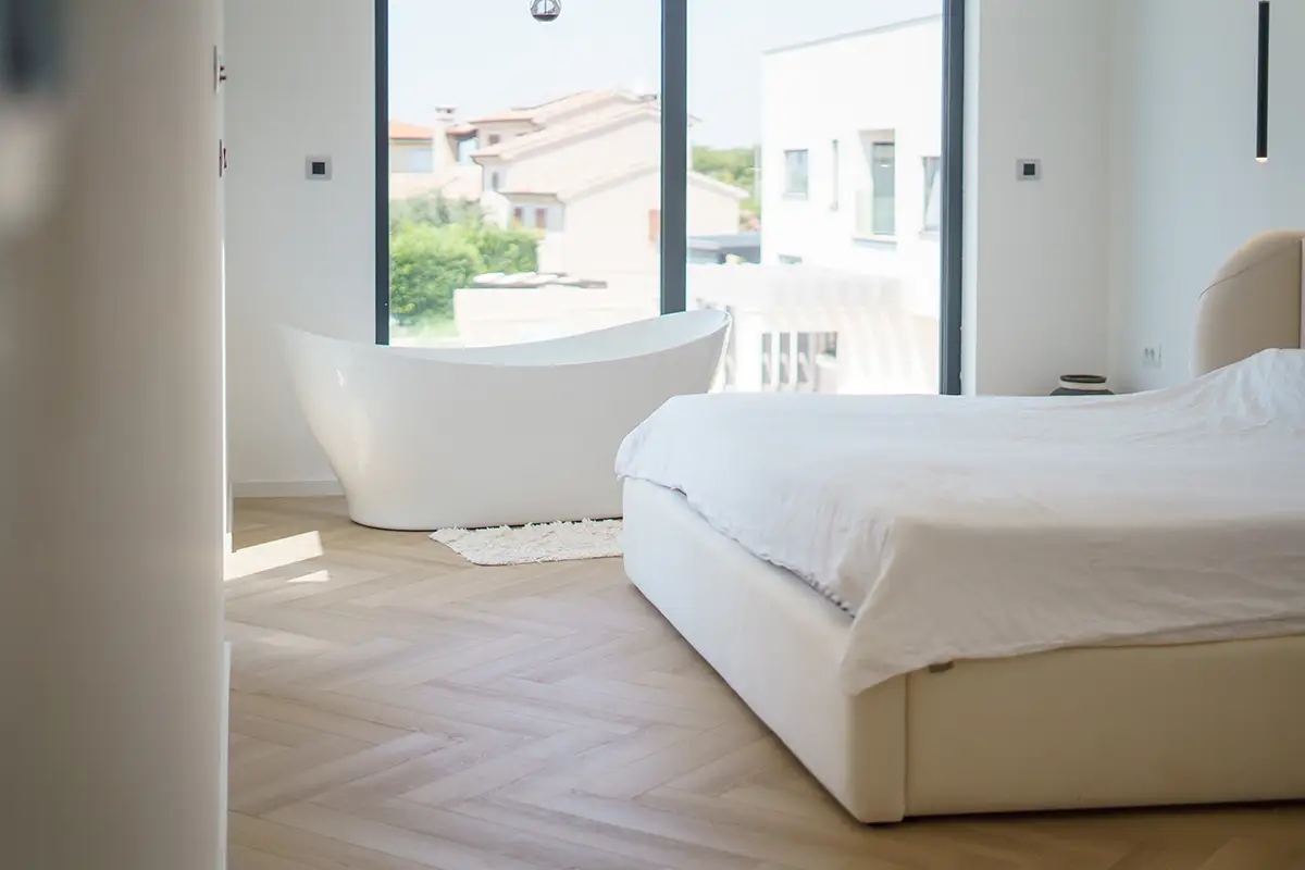 Svetla spalnica z elegantnimi lesenimi tlemi, ki poudarjajo toplino in naravno estetiko prostora 